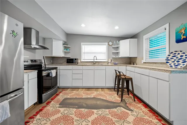 a kitchen with granite countertop a sink cabinets stainless steel appliances and a window