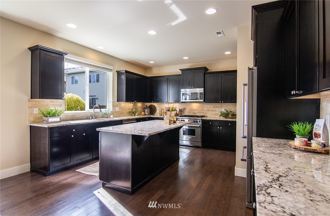 3924 185th Place Southeast Bothell, WA 98012 - Photo 7 of 25 a kitchen with kitchen island granite countertop wooden floors and a sink
