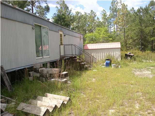 1213 Delaware Road DeFuniak Springs, FL 32433 - Photo 3 of 4 a backyard of a house with yard table and chairs
