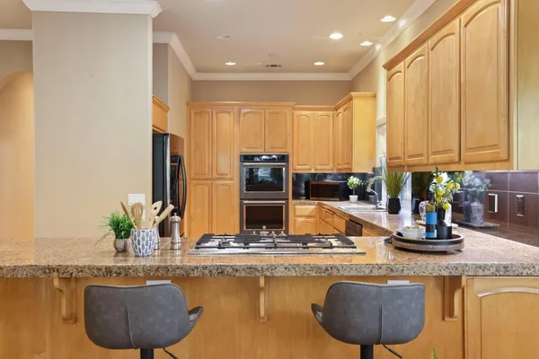 a kitchen with stainless steel appliances granite countertop a sink a stove and a wooden cabinets