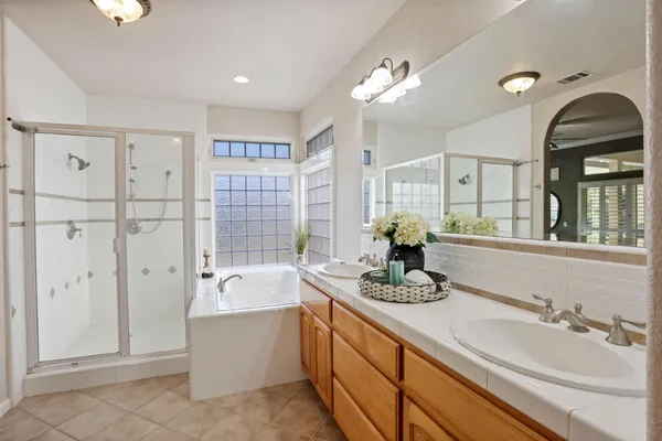 a bathroom with a double vanity sink large mirror and bathtub