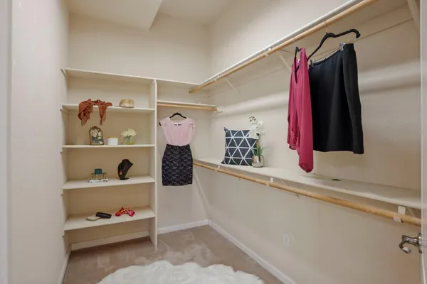 a view of walk in closet with clothes and shoes