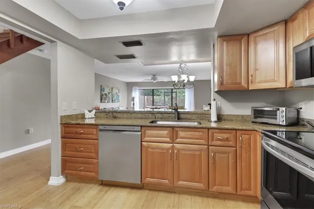 a kitchen with cabinets wooden floor and stainless steel appliances