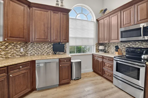 a kitchen with stainless steel appliances granite countertop a stove a sink dishwasher and a microwave oven with wooden floor
