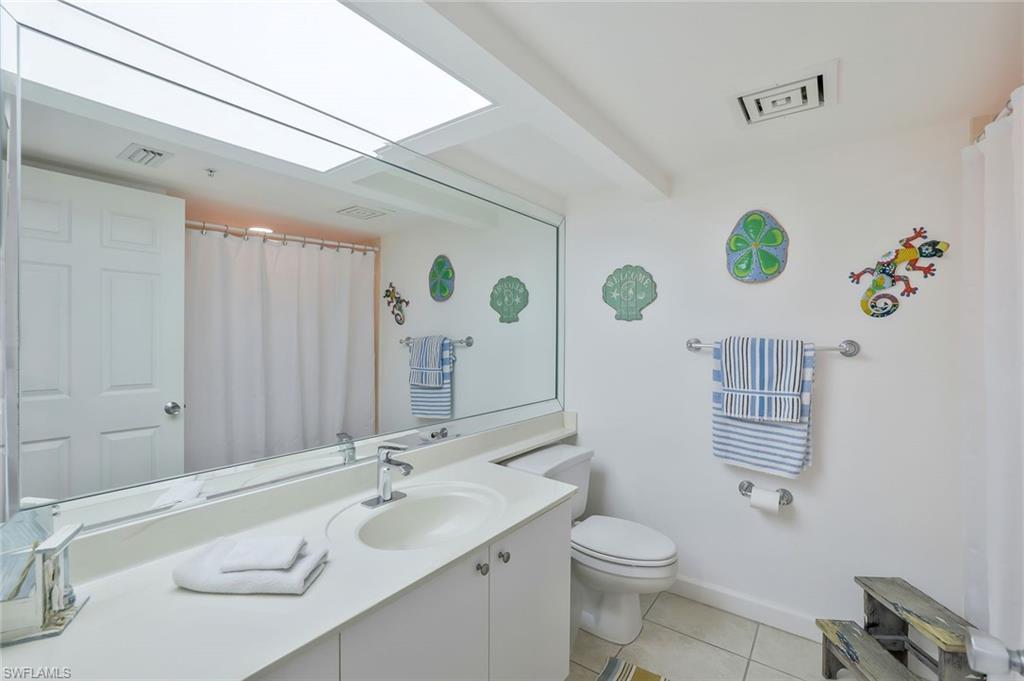 25 Bluebill Avenue, Unit 1103 Naples, FL 34108 - Photo 12 of 22 a bathroom with a sink a toilet and a mirror