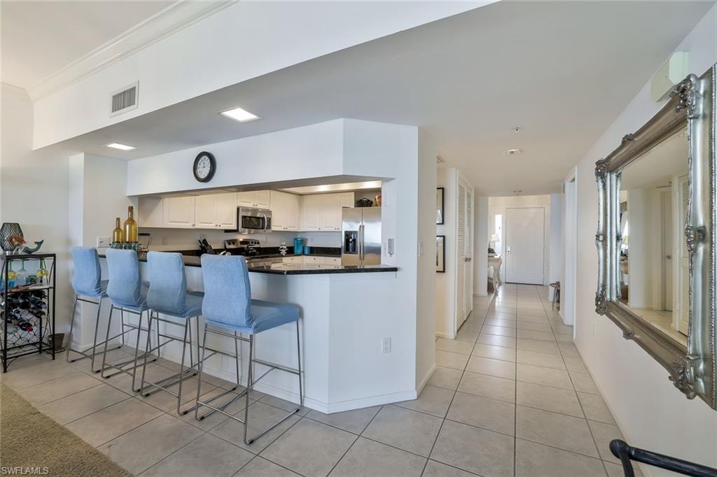 25 Bluebill Avenue, Unit 1103 Naples, FL 34108 - Photo 9 of 22 a kitchen with stainless steel appliances granite countertop a refrigerator and a stove top oven