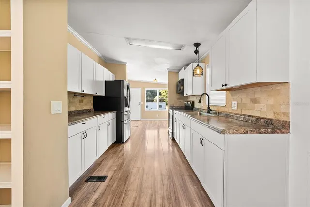 a large kitchen with granite countertop a large counter top space a sink stainless steel appliances and cabinets