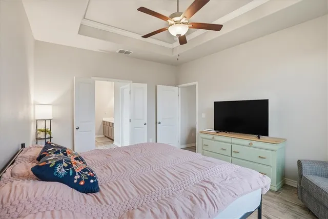 a bedroom with a bed and a flat tv screen on dresser