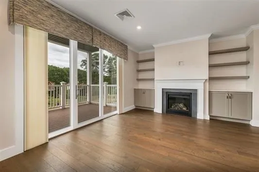 an empty room with wooden floor fireplace and windows