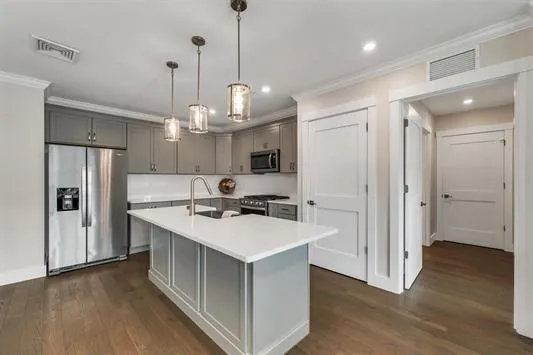 a kitchen with stainless steel appliances granite countertop a refrigerator a sink dishwasher a stove and white cabinets with wooden floor