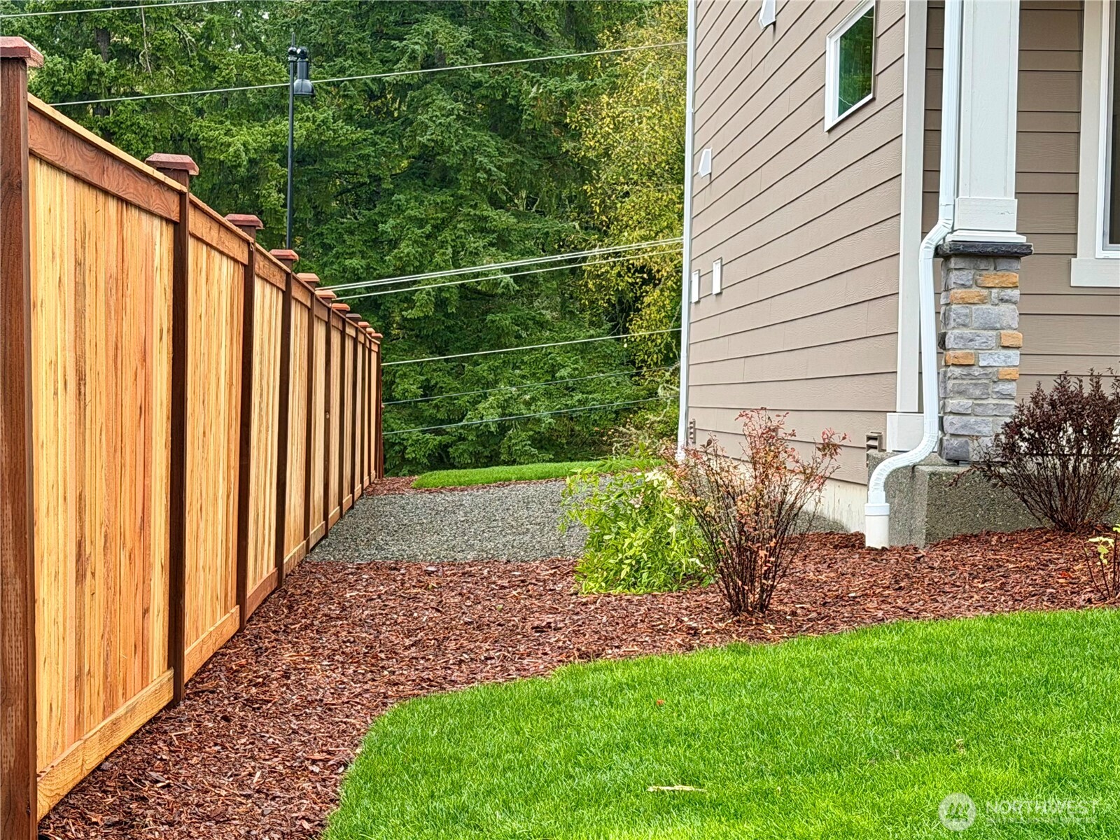 17529 Northeast Midnight Sun Loop Poulsbo, WA 98370 - Photo 3 of 36 a view of a backyard with plants and wooden fence