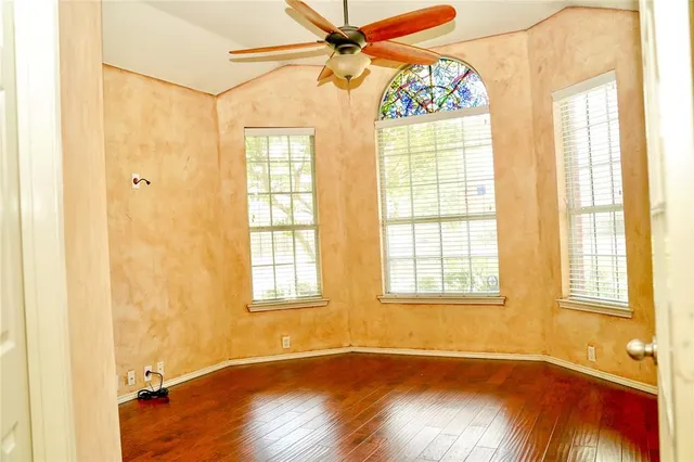 a view of an empty room with a window and wooden floor