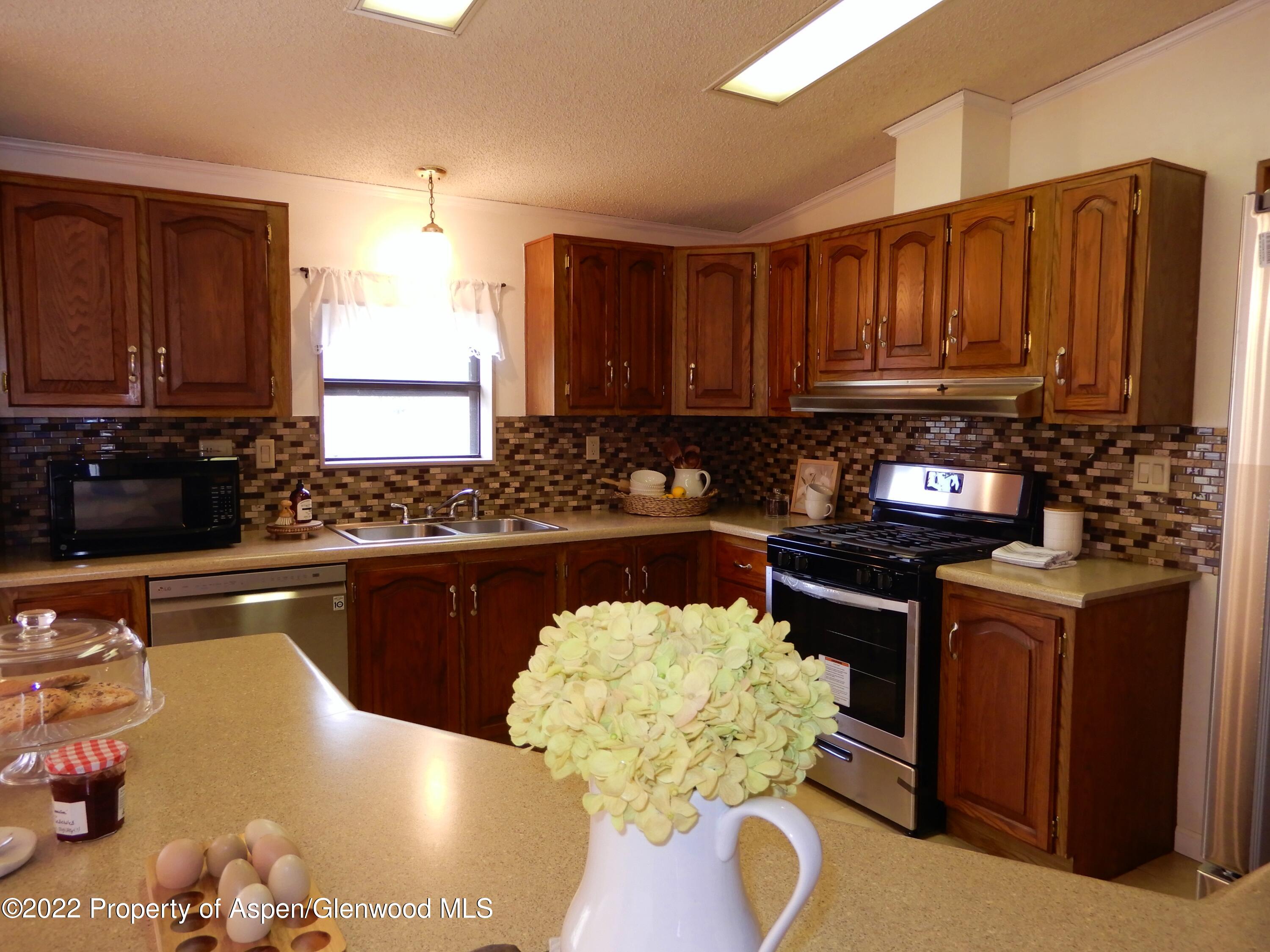 1110 Arnold Court Rifle, CO 81650 - Photo 9 of 23 a kitchen with granite countertop a stove a oven a sink dishwasher and cabinets with wooden floor