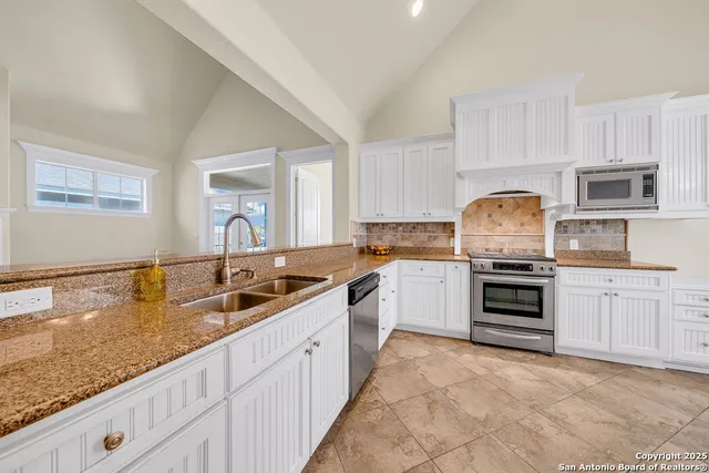 a kitchen with granite countertop a sink stainless steel appliances and cabinets