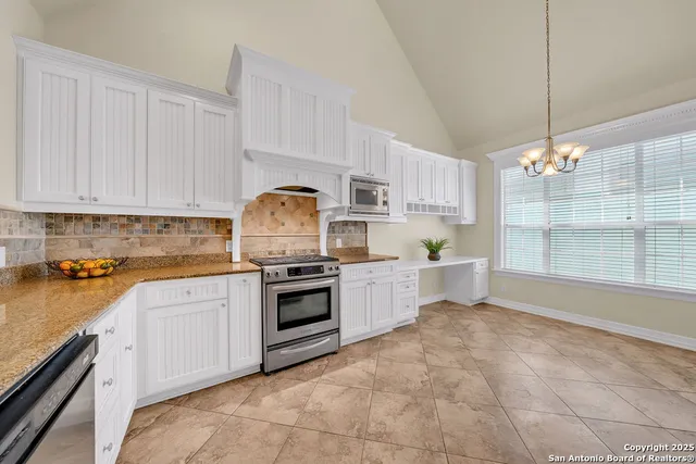 a kitchen with granite countertop a stove a sink a counter space and cabinets