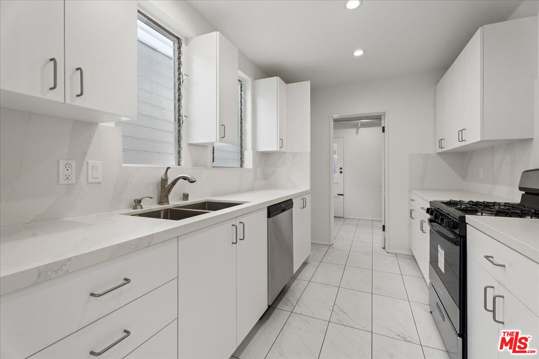 207 South Reeves Drive Beverly Hills, CA 90212 - Photo 3 of 13 a kitchen with a sink dishwasher stove and cabinets