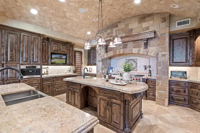a kitchen with stainless steel appliances granite countertop a sink a stove and a wooden cabinets