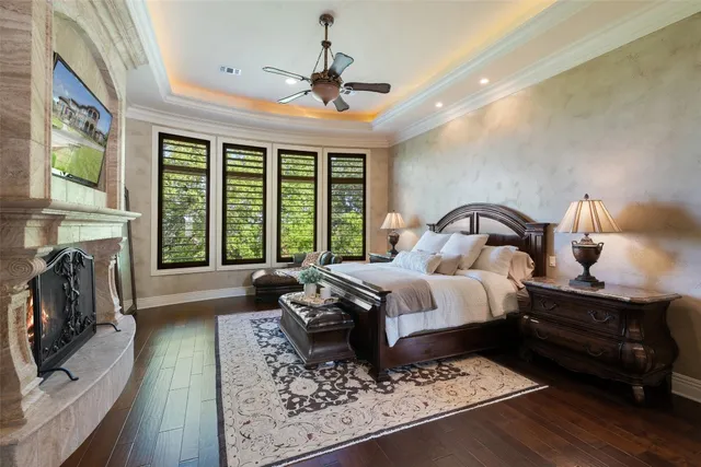 a spacious bedroom with a bed a fireplace and a flat tv screen on dresser