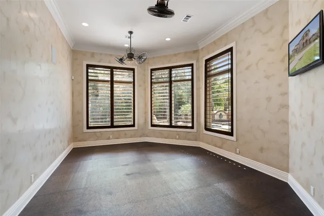 an empty room with windows and ceiling fan