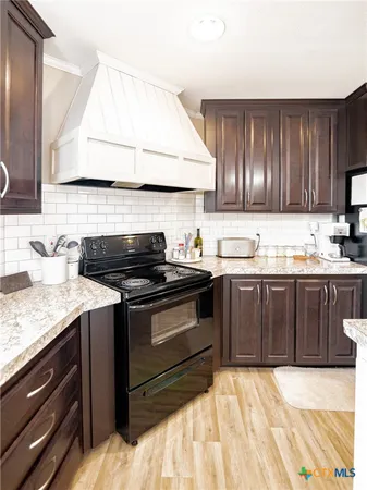 a kitchen with granite countertop wooden cabinets and a stove top oven