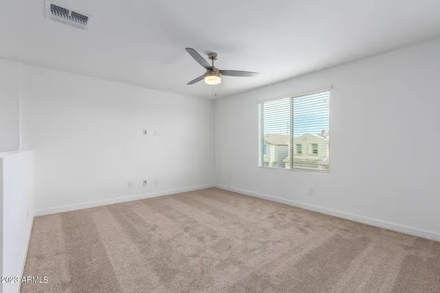 an empty room with ceiling fan and window