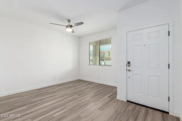 an empty room with wooden floor closet and windows