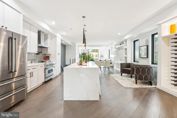 a kitchen with stainless steel appliances kitchen island granite countertop a refrigerator a stove a sink dishwasher and white cabinets with wooden floor