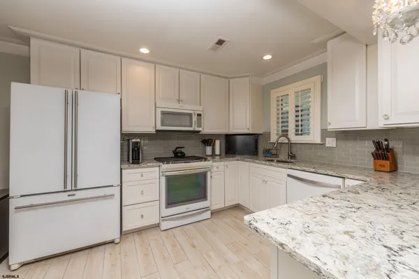 a kitchen with granite countertop white cabinets and white appliances