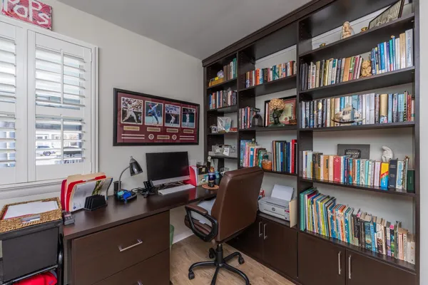 a view of a workspace with bookshelf and a window