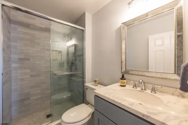 a bathroom with a granite countertop sink toilet and shower