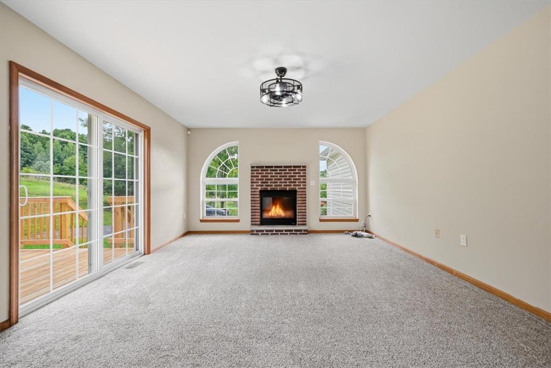 387 Blue Ridge Road Saylorsburg, PA 18353 - Photo 10 of 90 A well-lit living area features a charming fireplace, arched windows, and convenient sliding glass doors leading to a private outdoor space.