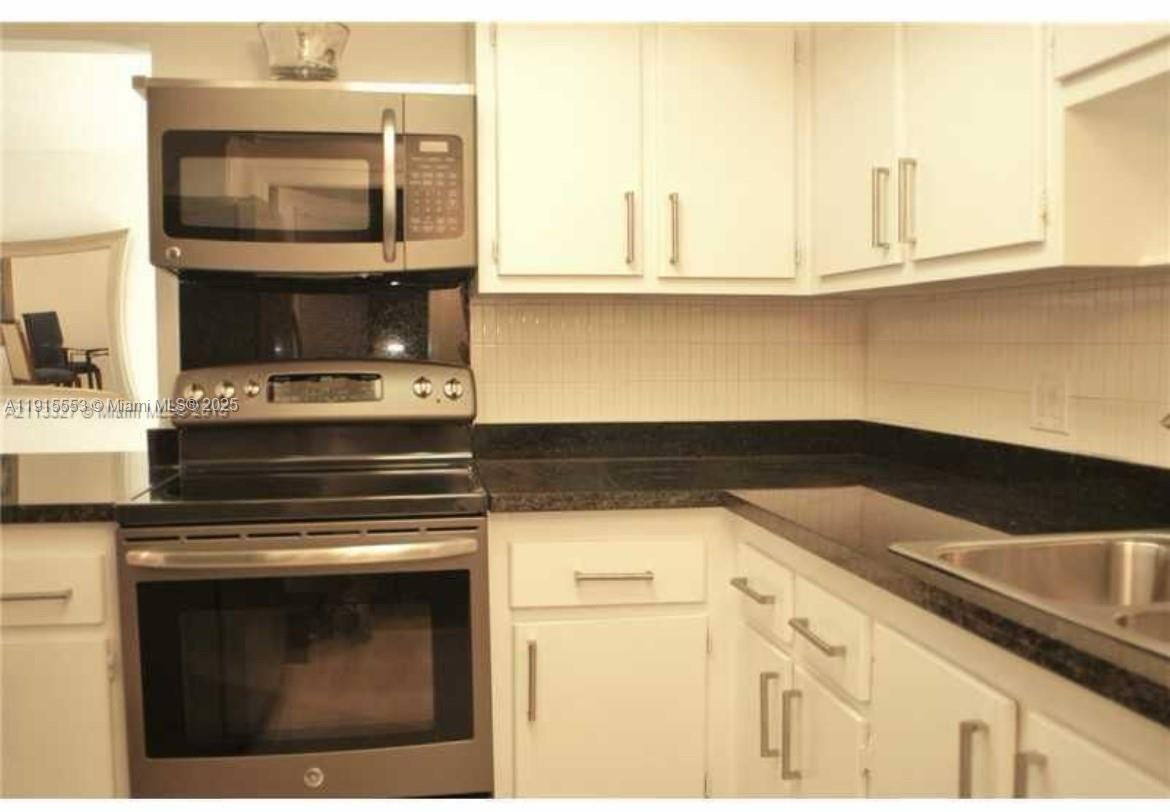 2451 Southwest 82nd Avenue, Unit 106 Davie, FL 33324 - Photo 4 of 10 a kitchen with granite countertop a stove and a microwave