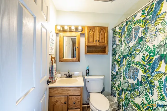 a bathroom with a granite countertop sink and a toilet