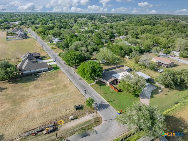 an aerial view of ocean with residential house with outdoor space and trees around