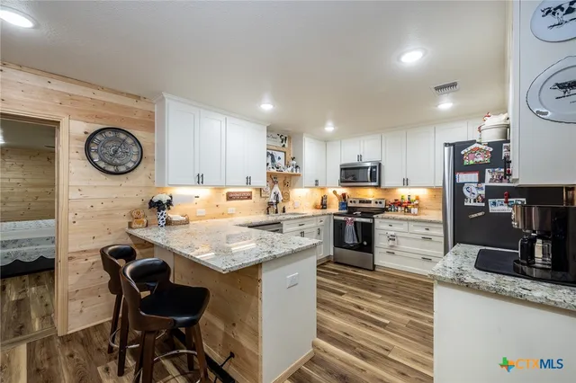 a kitchen with a stove a refrigerator and a dining table with wooden floor