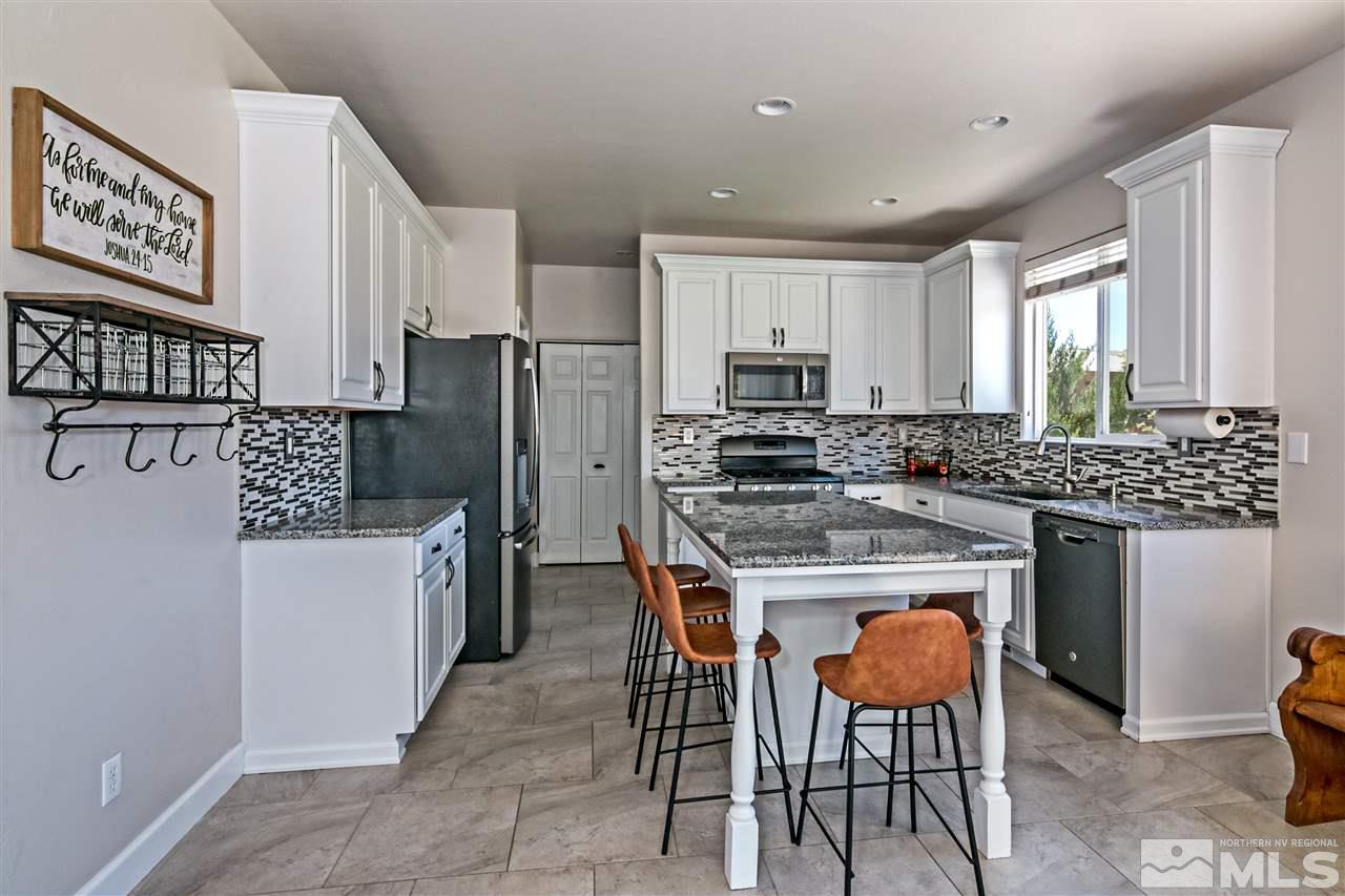 2330 Clementine Lane Reno, NV 89521 - Photo 9 of 32 a kitchen with stainless steel appliances kitchen island granite countertop a stove a refrigerator a sink a dining table and chairs