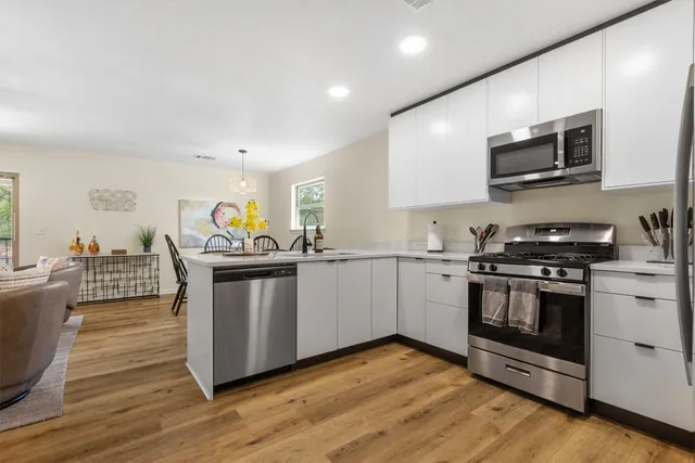 a kitchen with stainless steel appliances a stove a microwave and white cabinets