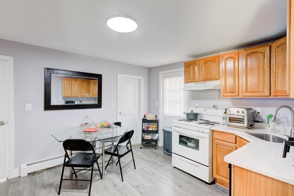 51 Prospect Street Woburn, MA 01801 - Photo 24 of 40 a kitchen with a stove top oven a sink dishwasher and white cabinets with wooden floor