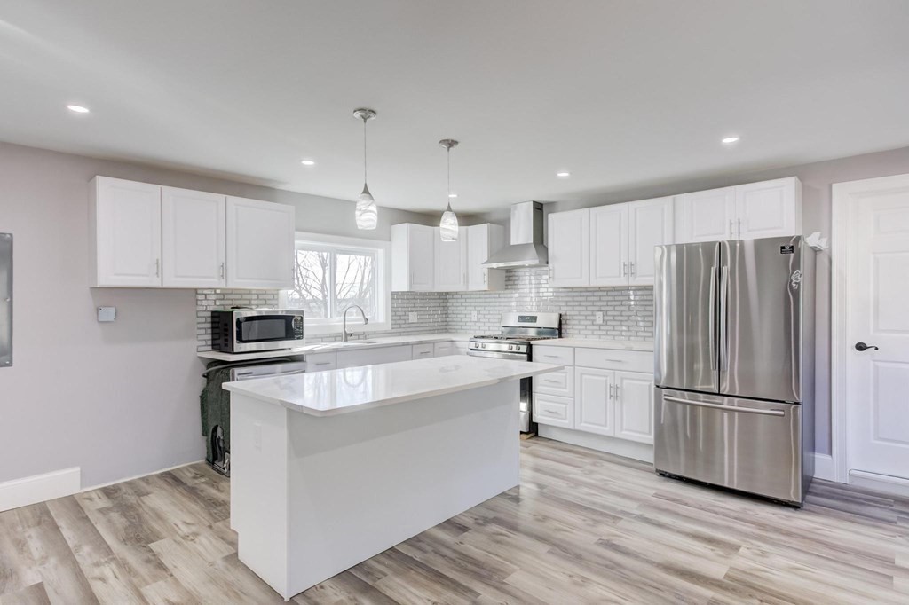 51 Prospect Street Woburn, MA 01801 - Photo 4 of 40 a kitchen with stainless steel appliances granite countertop a refrigerator a stove a sink and white cabinets with wooden floor