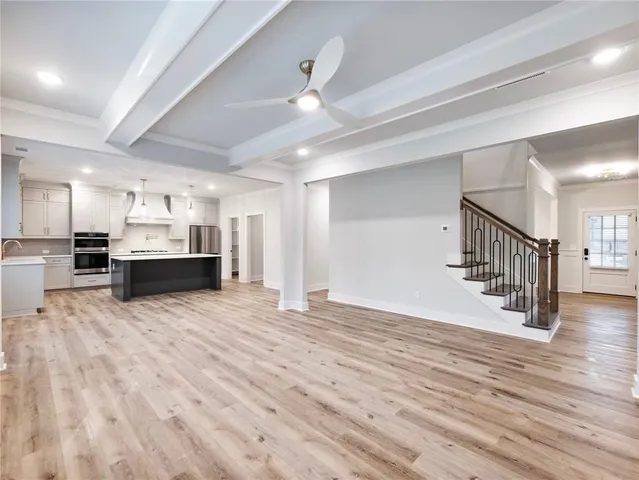 a large kitchen with kitchen island a sink dishwasher a refrigerator and white cabinets with wooden floor