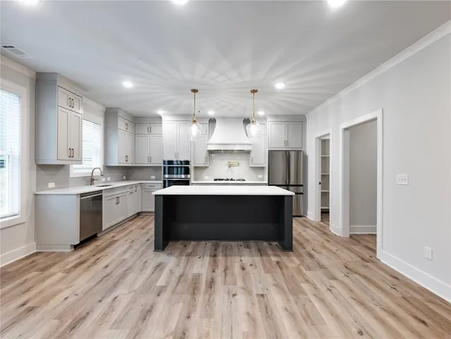 a kitchen with kitchen island a sink stainless steel appliances and wooden floor
