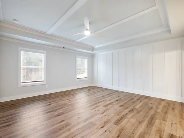 a view of empty room with wooden floor and fan