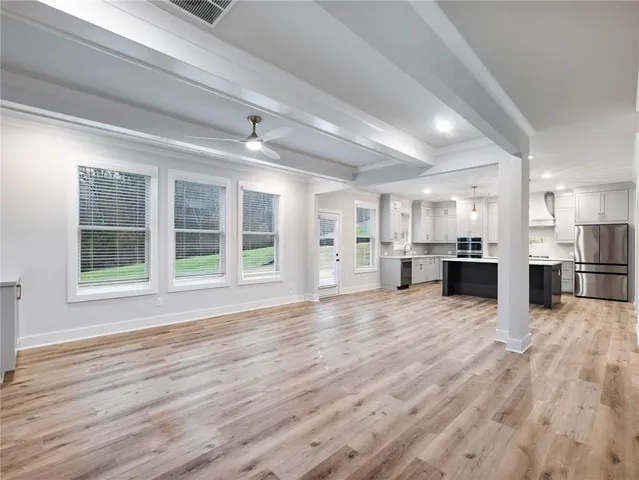 a view of an empty room with a window and wooden floor