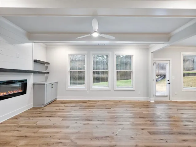 an empty room with wooden floor and a kitchen