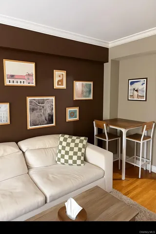 a living room with furniture a wall paintings and a window