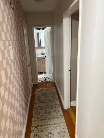 a view of a hallway with wooden floor and a bathroom