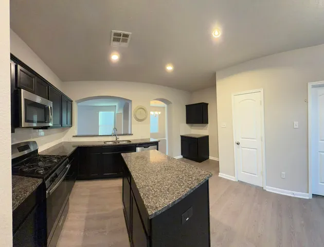 a large kitchen with stainless steel appliances a large counter top a stove and a refrigerator