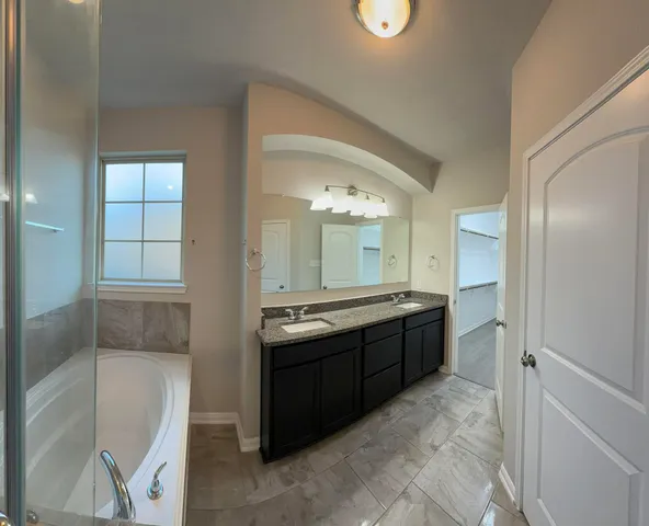 a large bathroom with a granite countertop tub sink and mirror