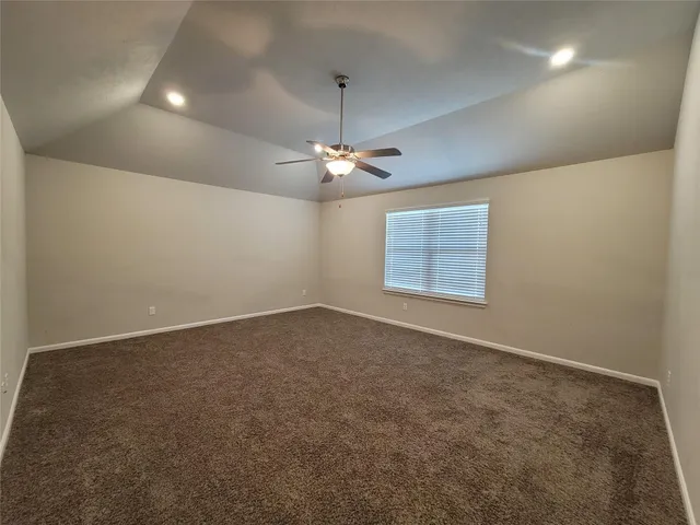 an empty room with a ceiling fan and carpet