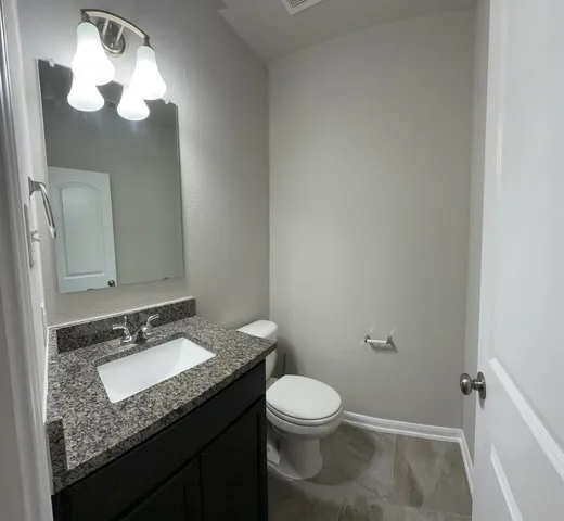 a bathroom with a granite countertop sink toilet and a mirror